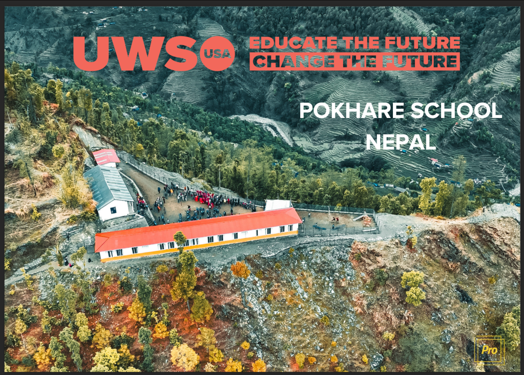 Aerial view of the newly constructed Pokhare School in Nepal, surrounded by hilly terrain and greenery, featuring people gathered around the building.